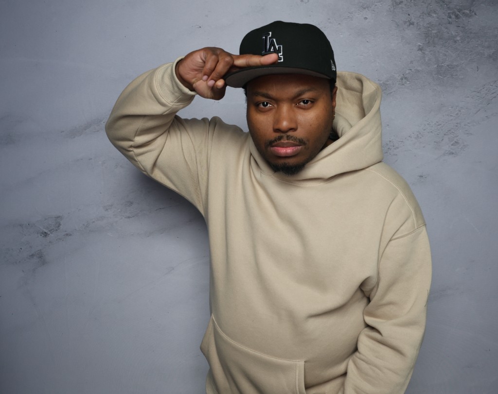 DJ Epidemik in studio, tan hoodie and Dodgers cap